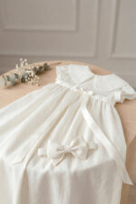 Bezuciskowa opaska niemowlęca w kolorze śmietankowym leżąca na lnianej sukience do chrztu Bella - komplet lilen.store